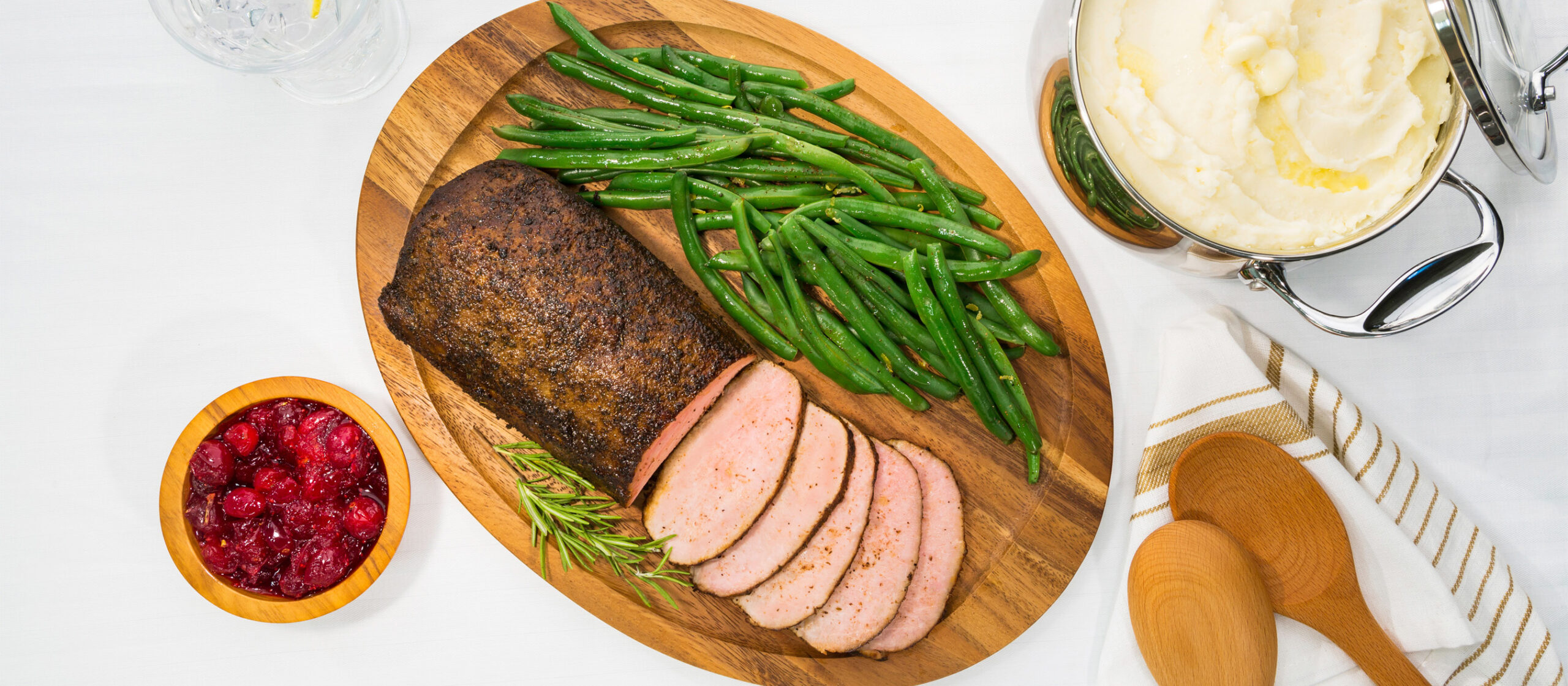 Overhead shot of an elegant holiday dinner of pork loin roast paired with cranberries, green beans, and mashed potatoes
